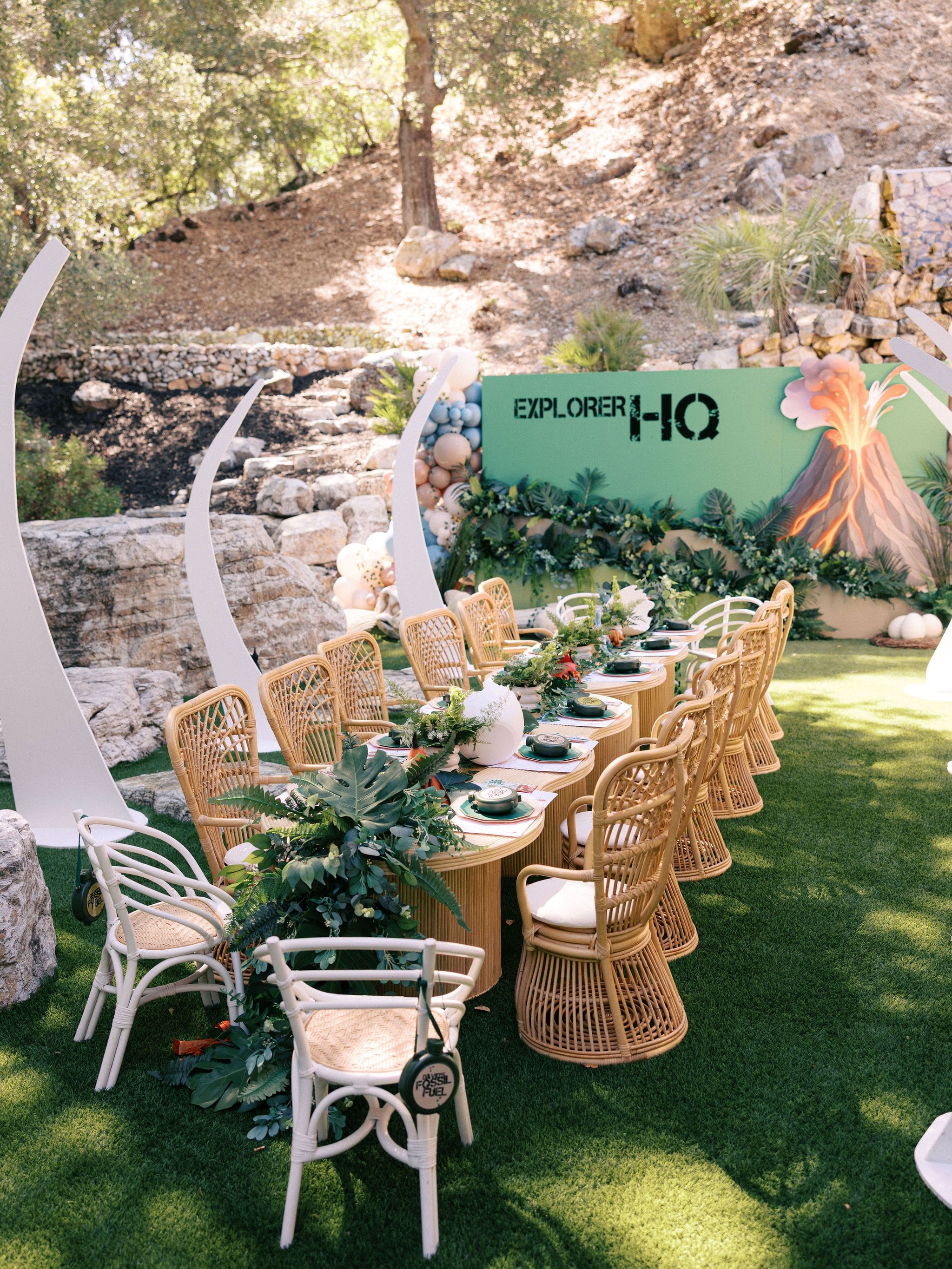 A long kids party table with rattan chairs outdoors